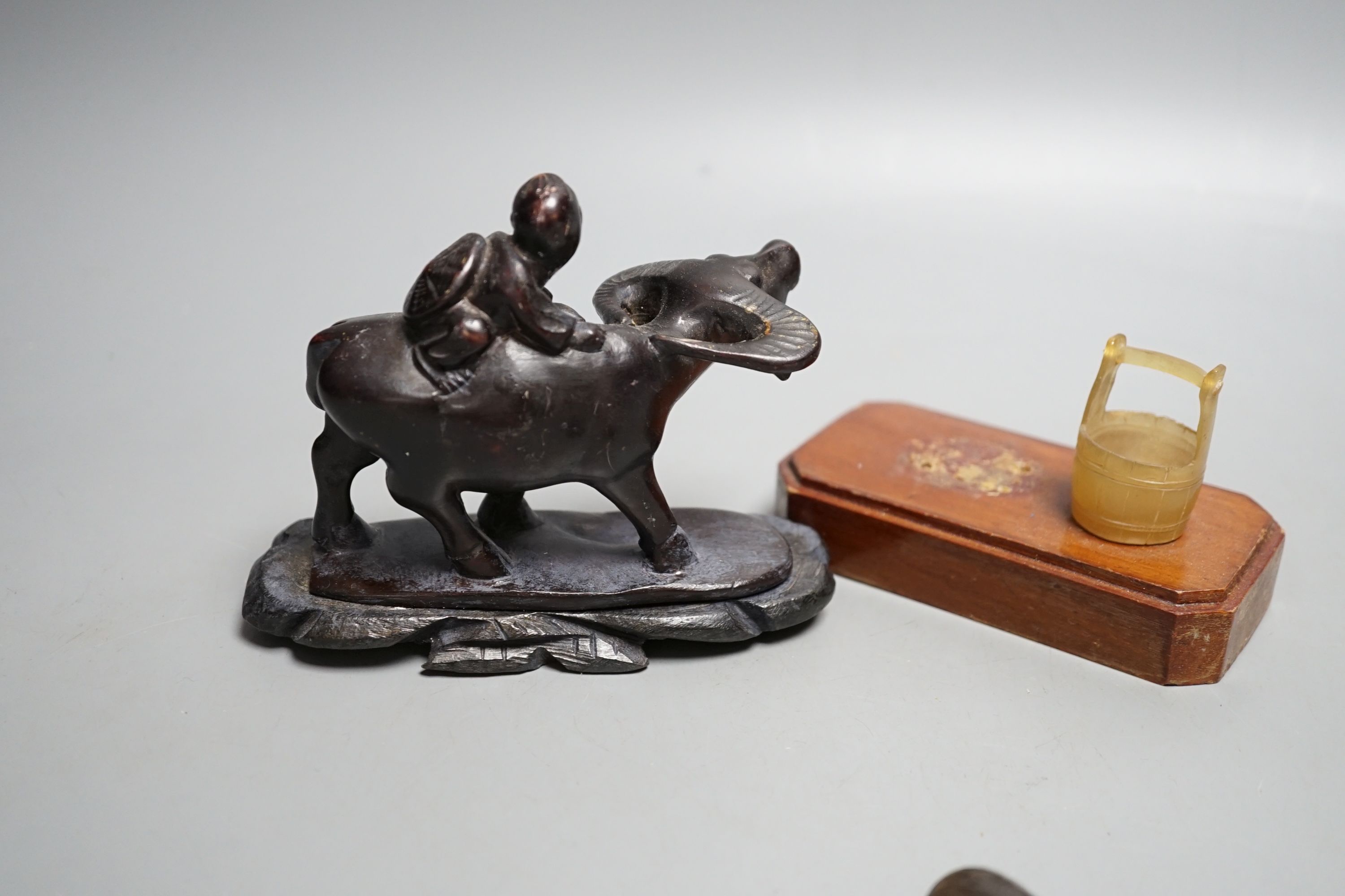 A Chinese horn figure and a carved hardwood figure riding a buffalo,13 cms wide.